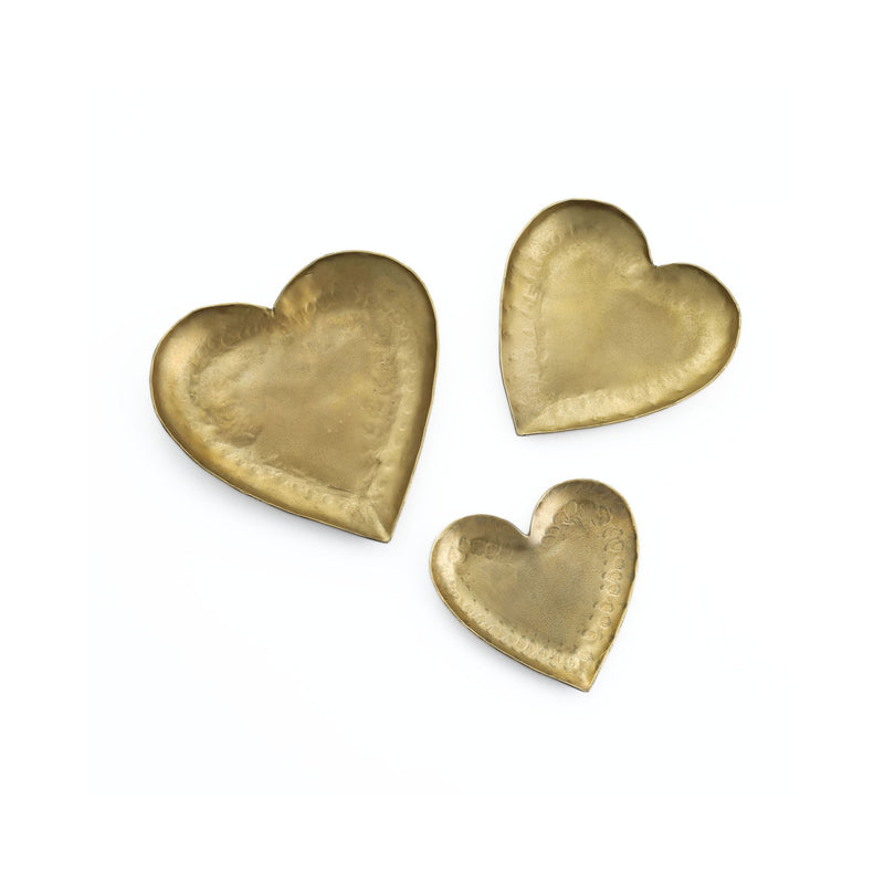 Set of three hammered brass iron heart-shaped catchalls from TOV Furniture, used as stylish serving bowls or decorative trays.