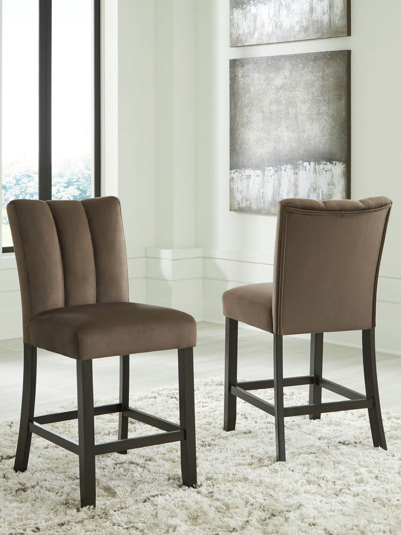 Two Jeshina upholstered barstools in mocha with wooden legs, part of Signature Design by Ashley® stool set, shown from a side view.
