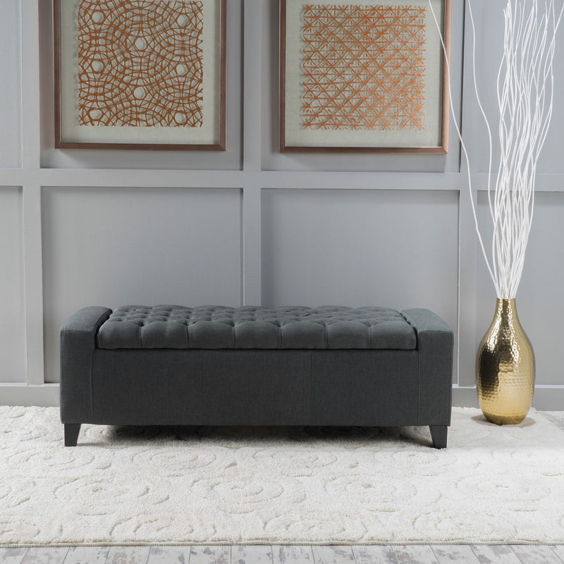 Dark gray Noble House storage ottoman with tufted top, contemporary design, and plush fabric, serving as a stylish storage solution.