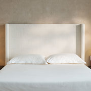 House & Home Furniture Hosford minimalist upholstered wingback bed with wood base platform in a modern bedroom setting.