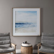 Framed print titled "Surf And Sand" by Uttermost featuring a serene beach scene with blue tones and a stylish frame.