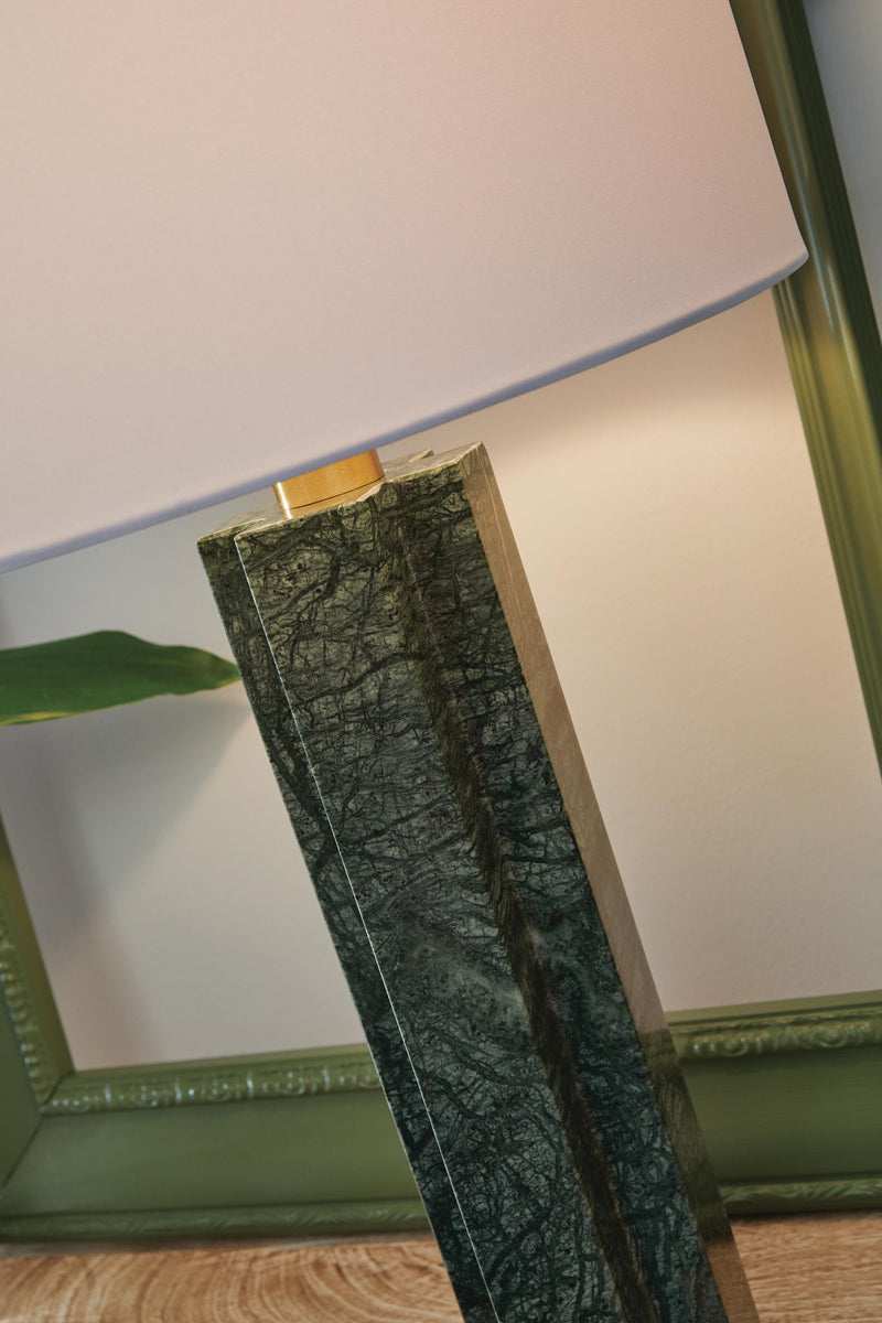 Signature Design by Ashley Keegan marble table lamp with green ceramic base and fabric shade on a wooden surface.