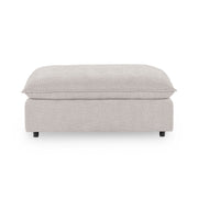 Classic Home Caplan upholstered ottoman with a cushioned top and wooden legs, ideal for living room or bedroom decor.